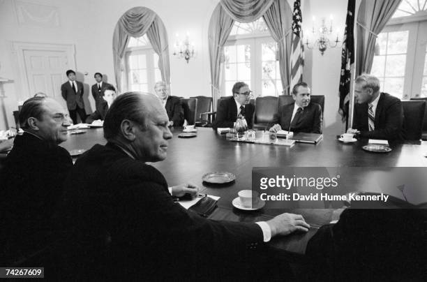 President Richard M. Nixon sits between Attorney General William B. Saxbe and Secretary of State Henry Kissinger before conducting his final cabinet...