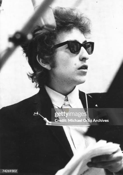 Bob Dylan takes a break with the harmonica around his neck and wearing Ray-Ban sunglasses while recording his album 'Bringing It All Back Home' on...