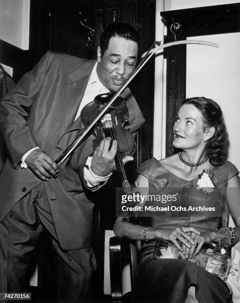 Composer Duke Ellington serenades heiress Doris Duke with a violin at the Embassy Auditorium in 1954 in Los Angeles, California.