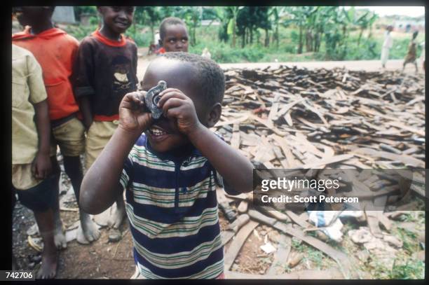 Children stand next to a pile of machetes that were used to kill Tutsis May 25, 1994 in Rwanda. Following the assassination of President Juvenal...