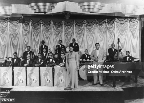 Portrait of the Chick Webb Orchestra featuring Ella Fitzgerald as they pose on stage, 1930s.