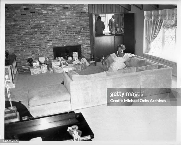 Soul singer Aretha Franklin relaxes at home with Christmas presents by the fireplace in circa 1980.