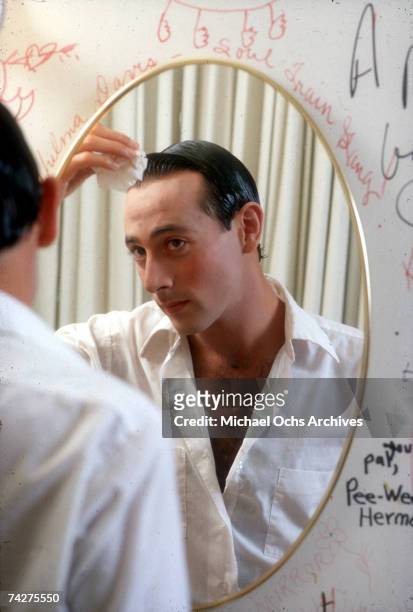 Actor Paul Reubens transforms himself in the mirror into his character Pee-wee Herman in May 1980 in Los Angeles, California.