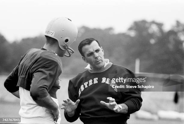 View of University of Notre Dame football coach Ara Parseghian as he speaks with one of his players during practice on the field, South Bend,...