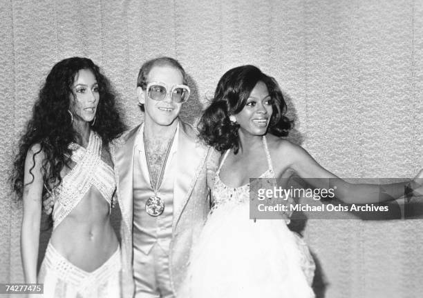 Pop singers Cher, Elton John and Diana Ross pose for a portrait backstage at the first Rock Music Awards which were held at the Santa Monica Civic...
