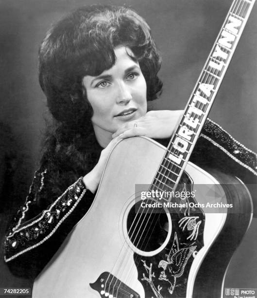 Loretta Lynn poses for a portrait holding a guitar that has her name spelled down the fretboard in circa 1961 in Nashville, Tennessee.