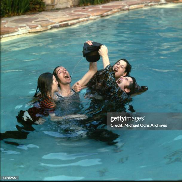 Mama Cass Elliott, John Phillips, Michelle Phillips, Denny Doherty of the folk group "The Mamas And The Papas" pose for a portrait session in a pool...