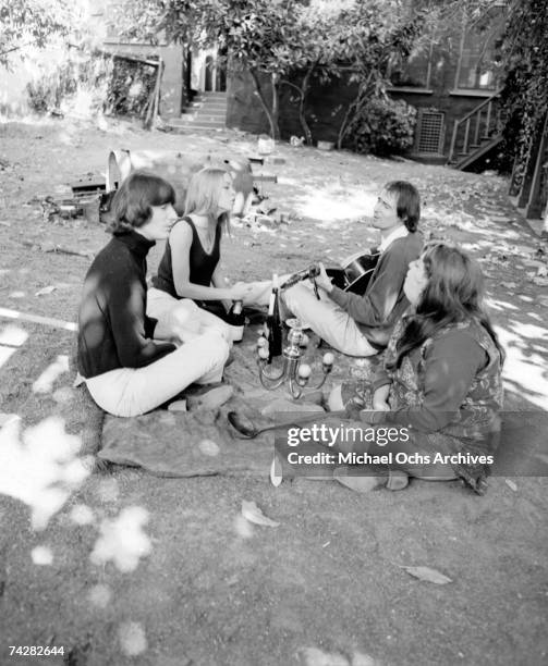 Denny Doherty, Michelle Phillips, John Phillips and Mama Cass Elliott have an acoustic guitar jam and picnic in circa 1966 in a park.