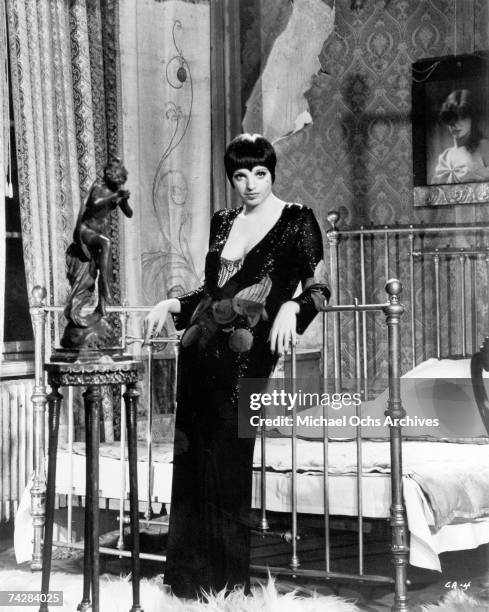 Liza Minnelli, US actress and singer, wearing a low-cut, long black dress, posing beside a bed in a publicity still issued for the film, 'Cabaret',...
