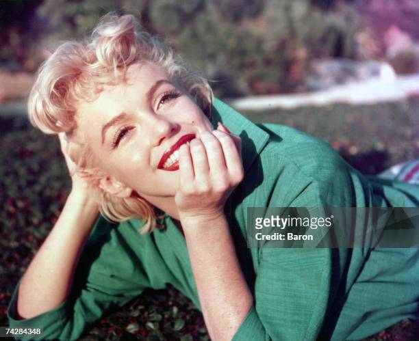 Actress Marilyn Monroe poses for a portrait laying on the grass in 1954 in Palm Springs, California.
