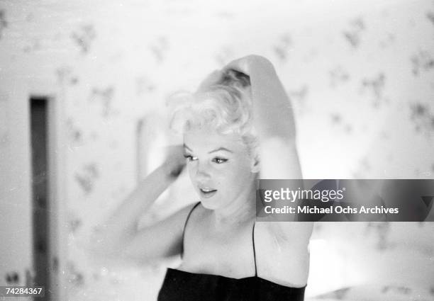 Actress Marilyn Monroe prepares to go out to the play "Cat On A Hot Tin Roof" by applying make-up and perfume in her hotel room at the Ambassador...