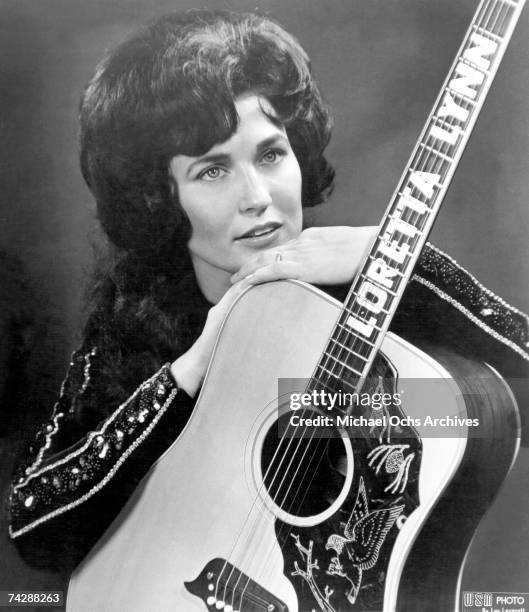 Loretta Lynn poses for a portrait holding a guitar that has her name spelled down the fretboard in circa 1961 in Nashville, Tennessee.