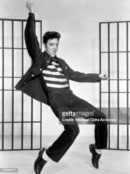 American actor and singer Elvis Presley dancing in a stylized prison uniform in a promotional portrait for director Richard Thorpe's film, 'Jailhouse...
