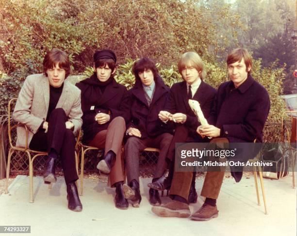 Rock and roll band "The Rolling Stones" pose for a portrait sitting on chairs on a patio in 1964. Mick Jagger, Keith Richards, Bill Wyman, Brian...