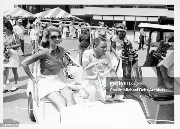 Pop singer Frank Sinatra rides on a golf cart with Barbara Marx, whom he would later marry, at a celebrity golf tournament in October 1971.