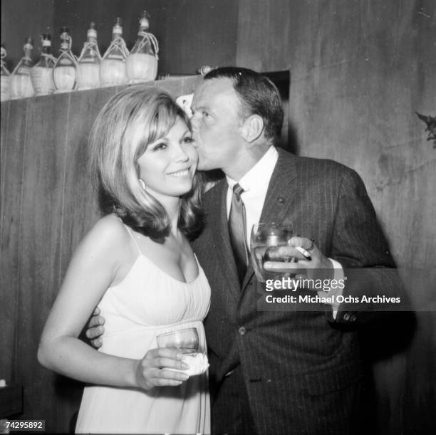 Pop singer Frank Sinatra enjoys a cocktail at an event with his daughter singer Nancy Sinatra in circa 1967.