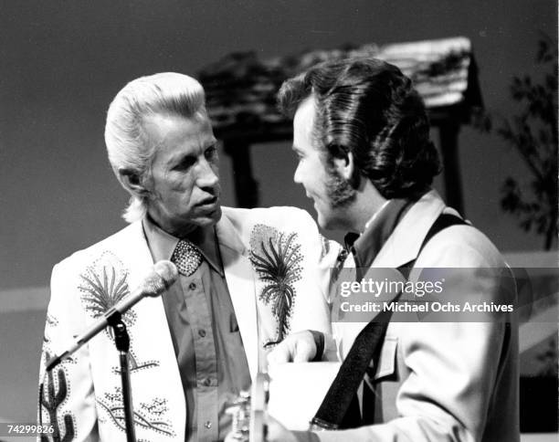 Country singer Porter Wagoner interacts with a man holding an acoustic guitar in circa 1970. Mr. Wagoner is wearing a Nudie Suit designed by Nudie...