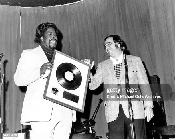 Singer, songwriter and producer Barry White receives a gold record for producing the album "Under The Influence Of..." by his back-up group Love...