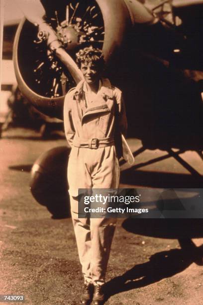 Photo of pilot Amelia Earhart standing by her plane.