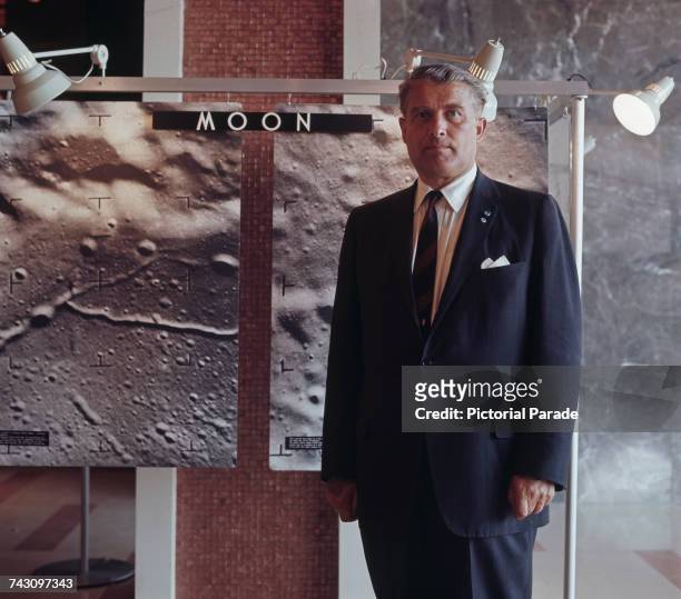 German-born American rocket scientist, Wernher von Braun standing next to large photographs of the lunar surface, USA, circa 1965.