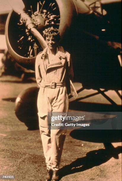 Photo of pilot Amelia Earhart standing by her plane.