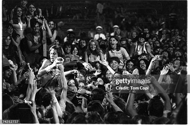 Iggy Pop of the Stooges entertains the crowd with a jar of peanut butter during a performance at the Cincinnati Pop Festival at Crosley Field,...