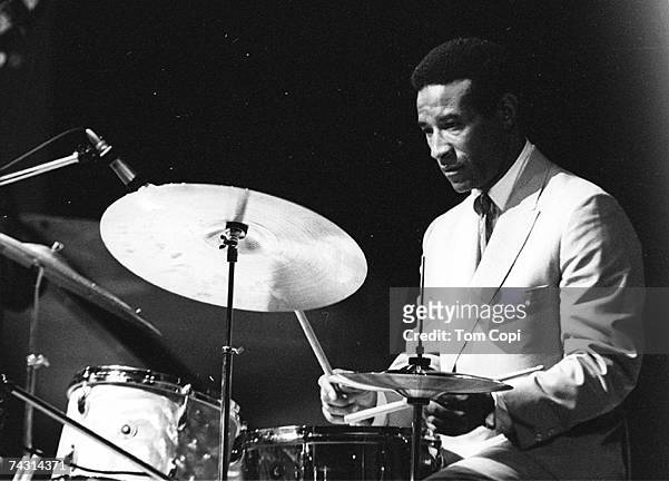 Jazz drummer Max Roach performs onstage wearing a white suit at the Newport Folk Festival on July 2, 1967 in Newport, Rhode Island.