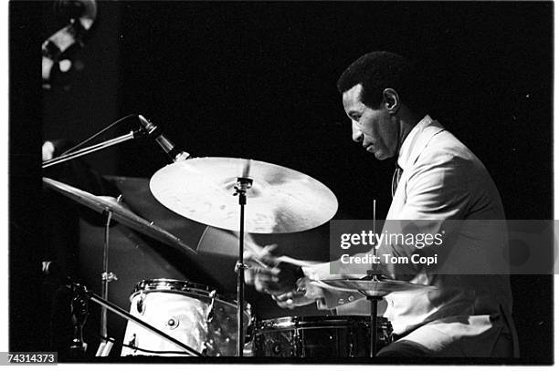 Jazz drummer Max Roach performs onstage wearing a white suit at the Newport Folk Festival on July 2, 1967 in Newport, Rhode Island.
