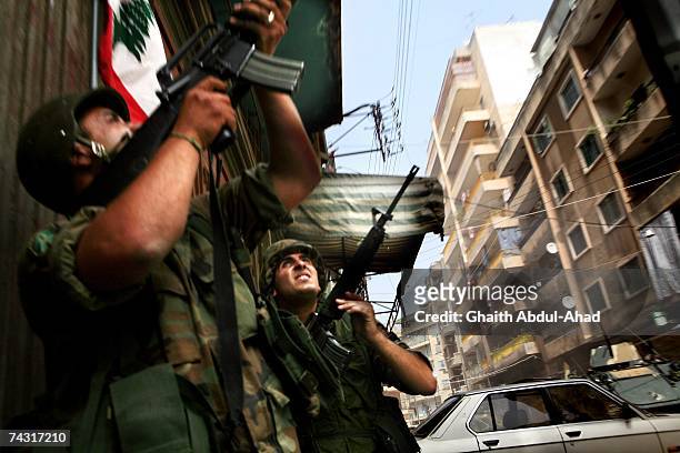 Soldiers from the Lebanese army look up to where gunmen from Fath el-Islam had barricaded themselves, as they fight their way down the street, on May...