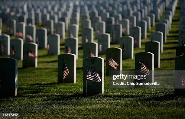 Small US flags wave in the wind after being placed in front of headstones at Arlington National Cemetery during the Flag-In Ceremony ahead of the...