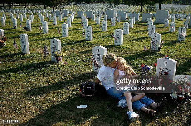 Stephanie Dostie of Ft. Campbell, Kentucky, holds her daughter Bayleigh Dostie while they sit next to the grave of their husband and father, Sgt....