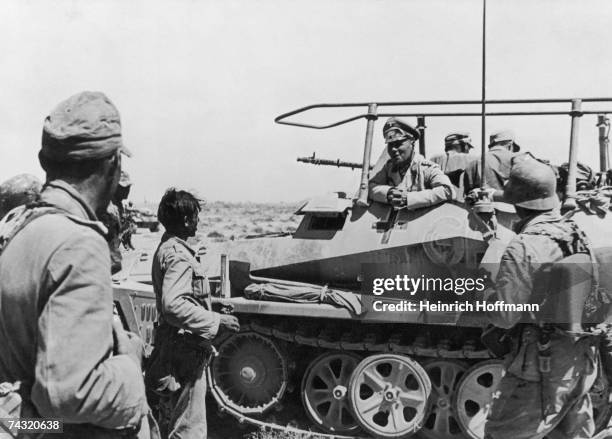 German military commander Erwin Rommel talks to soldiers of the German Deutsches Afrikakorps from his SdKfz 250 GREIF half-track armored personnel...