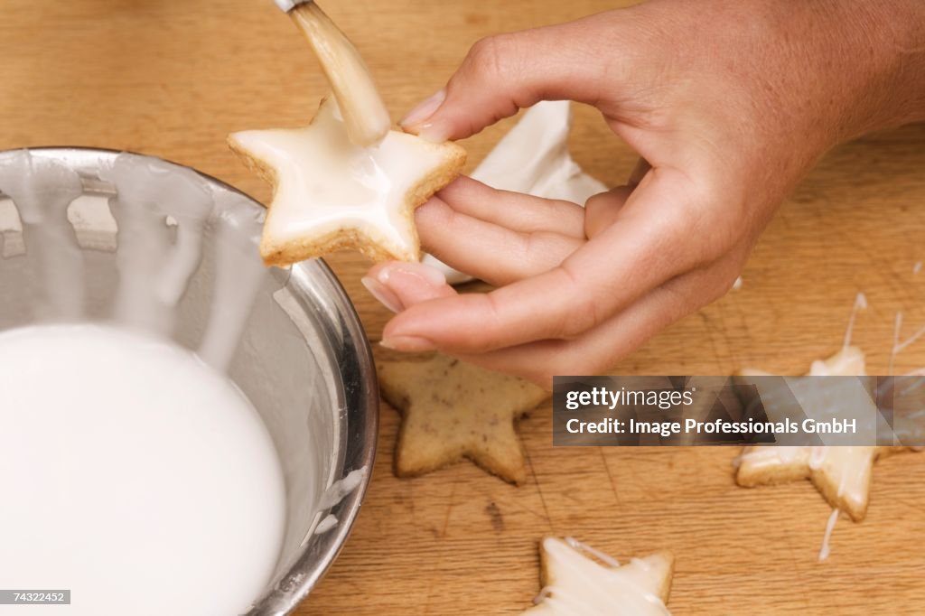 Brushing star-shaped biscuits with glace icing