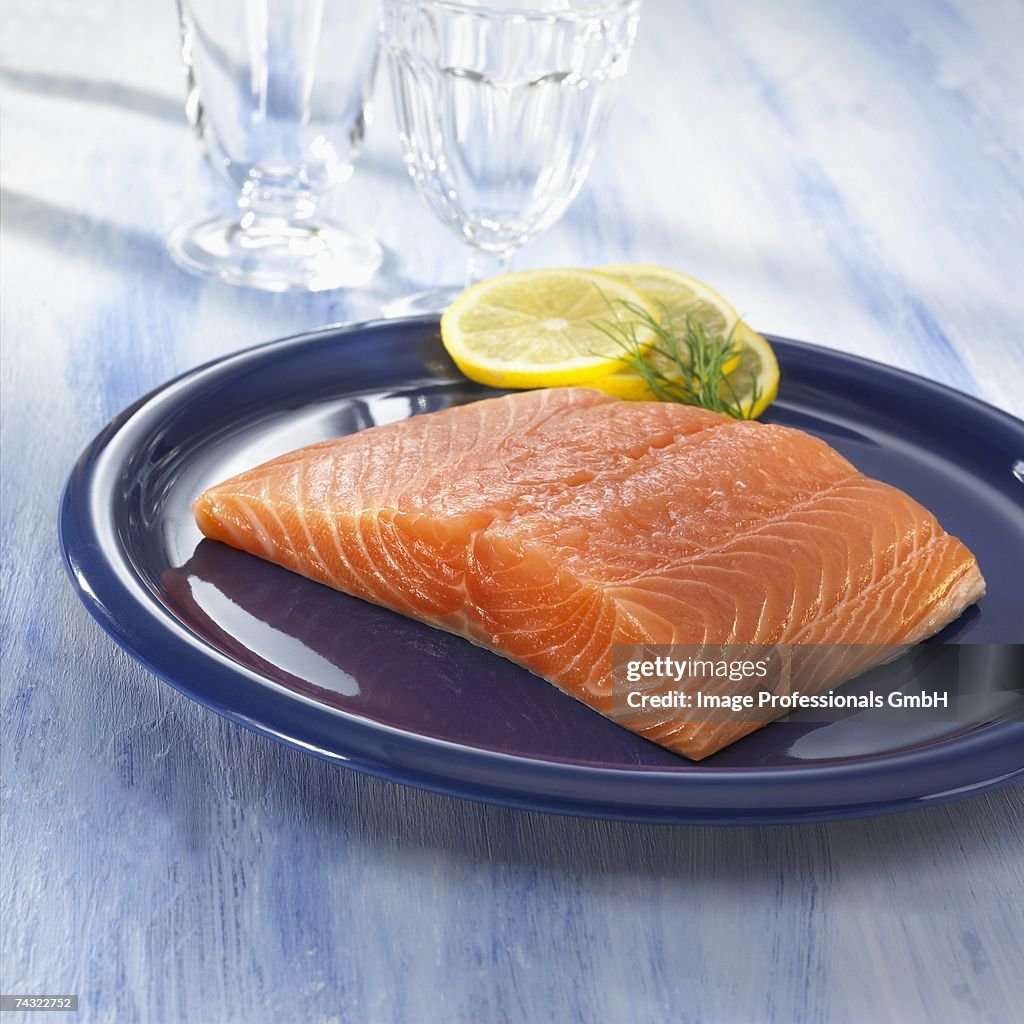 A salmon fillet with slices of lemon on a plate