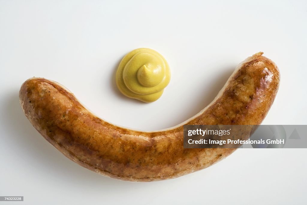 A sausage with mustard on a white background