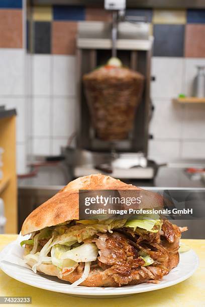 a doner kebab with meat on spit in background - kebab stock-fotos und bilder