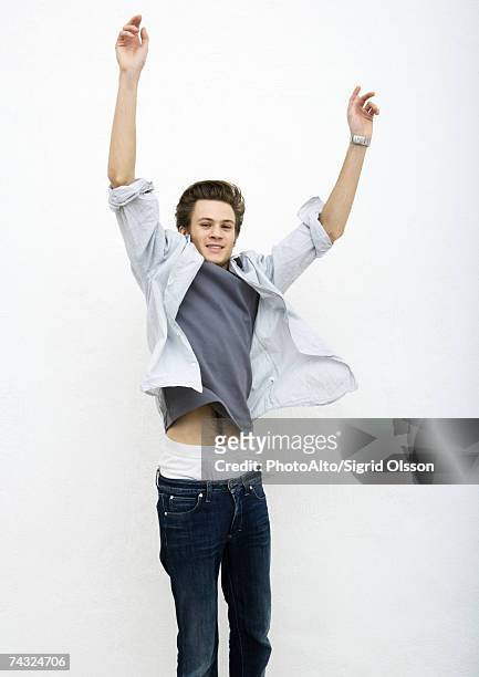 young man jumping with arms in air - pantalón de cintura baja fotografías e imágenes de stock