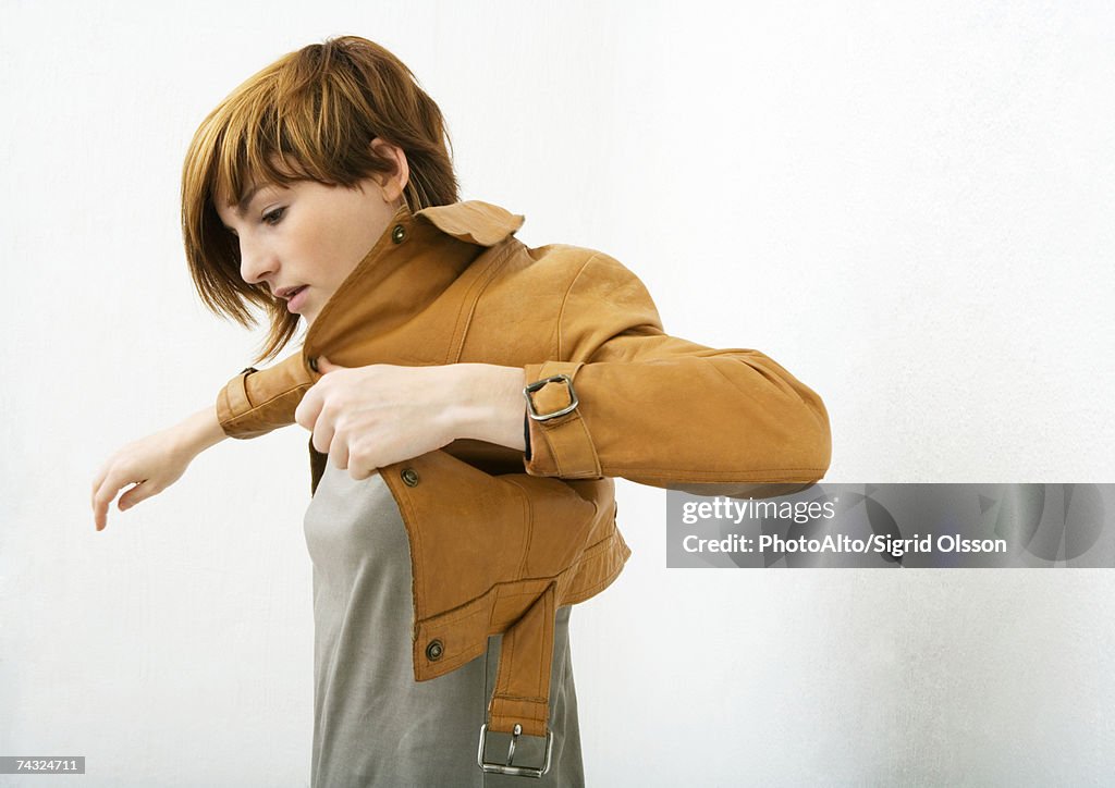 Young woman putting on jacket