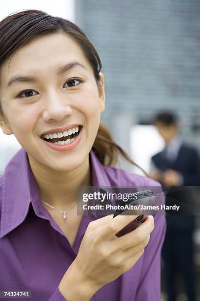 young woman holding cell phone, laughing - purple blouse stock pictures, royalty-free photos & images