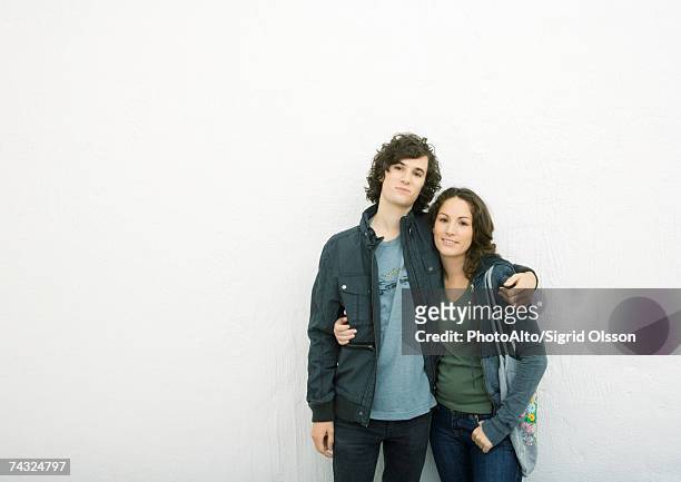 young couple standing with arms around each other, looking at camera - looking around on white background stock pictures, royalty-free photos & images