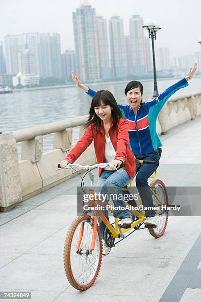 two friends riding tandem bicycle - hands free cycling - fotografias e filmes do acervo
