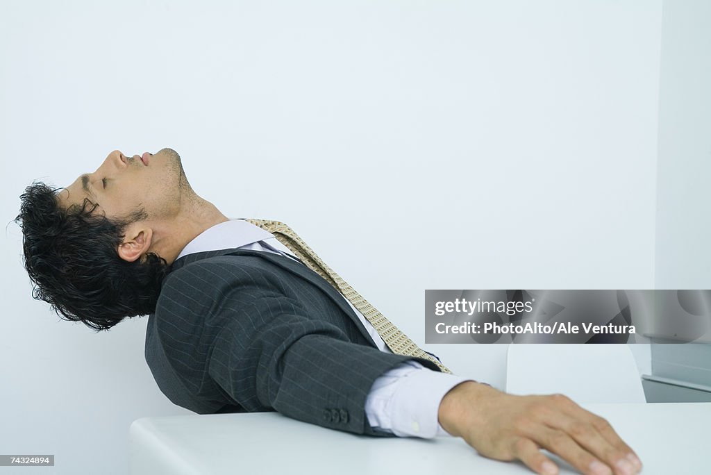 Businessman sitting with head back and eyes closed