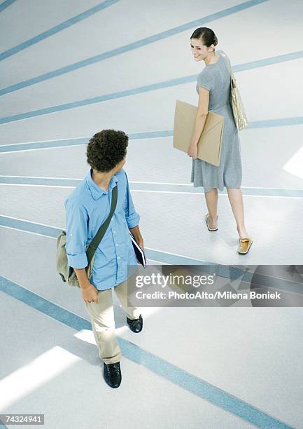 man and woman looking over shoulders at each other in passing, full length, high angle view - vorbeigehen stock-fotos und bilder