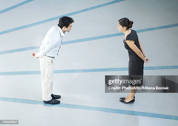 man and woman standing face to face, hands behind back, leaning toward each other, full length, high angle view - man standing full length side stock-fotos und bilder