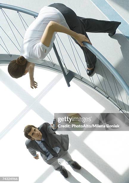 businessman holding cell phone up to woman from lower floor, full length, high angle view - businesswoman under stock-fotos und bilder