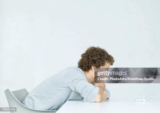 teenage boy with head down on arms, looking at cell phone - bad posture stock pictures, royalty-free photos & images