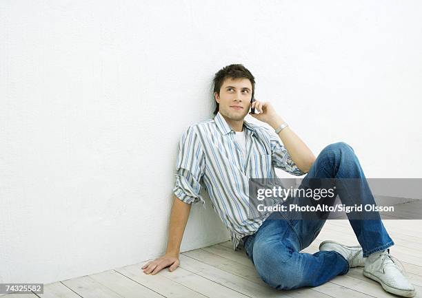 young man sitting on floor, using cell phone - male knee stock pictures, royalty-free photos & images