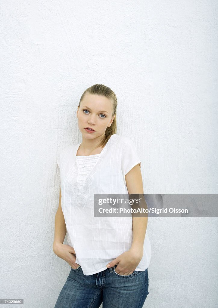 Teenage girl leaning against wall, looking at camera, portrait