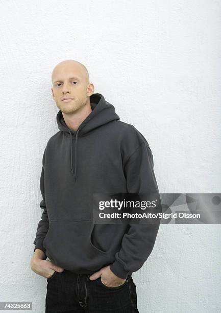 young man standing with hands in pockets, looking at camera, portrait - camisa con capucha fotografías e imágenes de stock