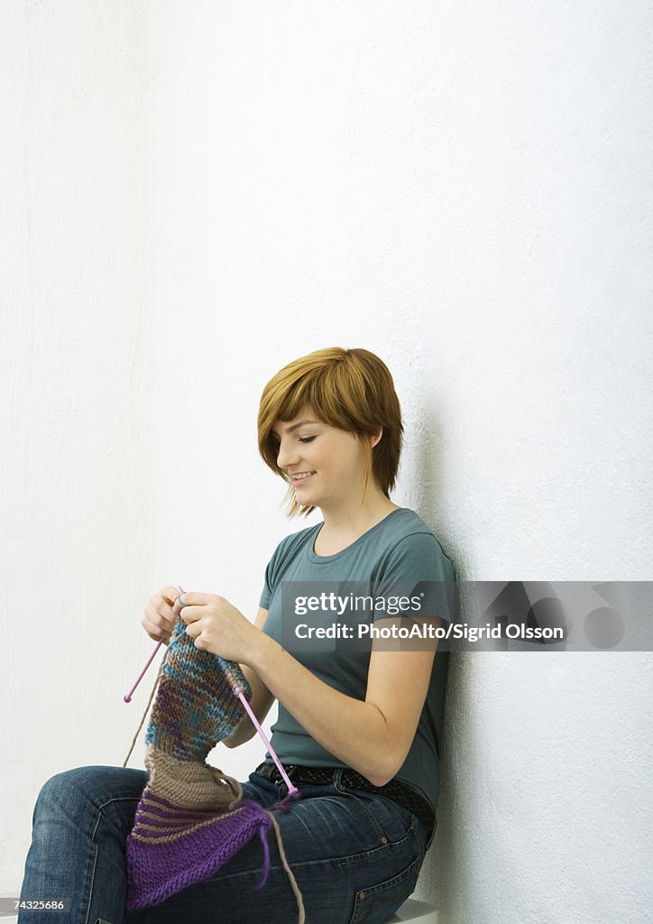 Young woman knitting, white background